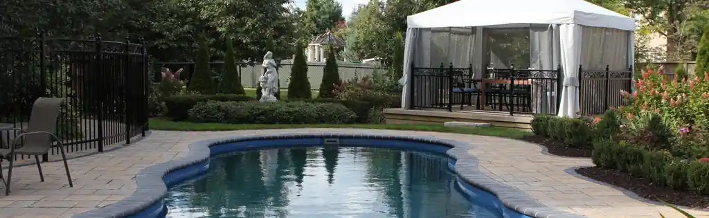 Blue pool with a gazebo beside it and planting along the edge