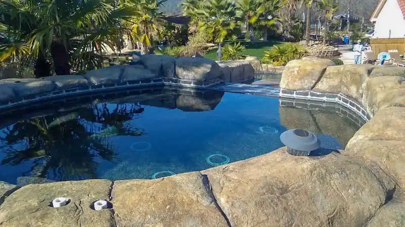 Faux rock edge and decorative concrete deck around a blue pool