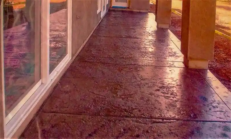 Stamped and colored concrete walkway curving beside a planted bed