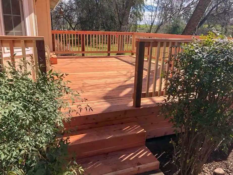 Redwood deck with wide stairs stepping down into a back yard