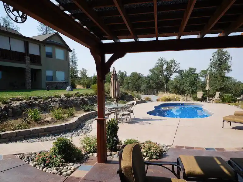 Pool framed by a pergola, planting beds and a lawn